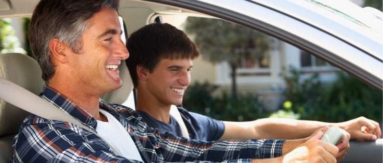 Dad telling car jokes while driving with his son.