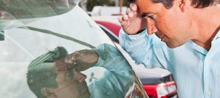 A person examining a demo car at a dealership, pondering the advantages and disadvantages.