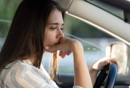 Young lady feeling buyer's remorse after buying a new car.