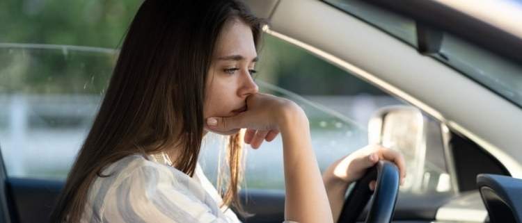 Young lady feeling buyer's remorse after buying a new car.