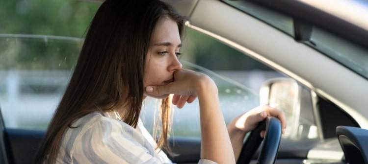 Young lady feeling buyer's remorse after buying a new car.