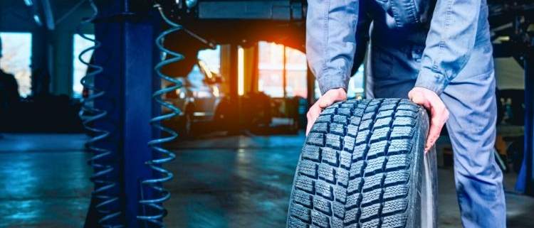 A mechanic rotating car tires in a garage, emphasizing the importance of regular tire rotations.