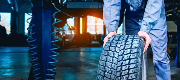 A mechanic rotating car tires in a garage, emphasizing the importance of regular tire rotations.