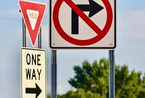 A driver confused by bizarre road signs representing weird traffic laws around the world.