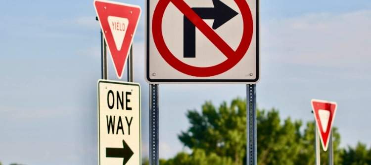 A driver confused by bizarre road signs representing weird traffic laws around the world.